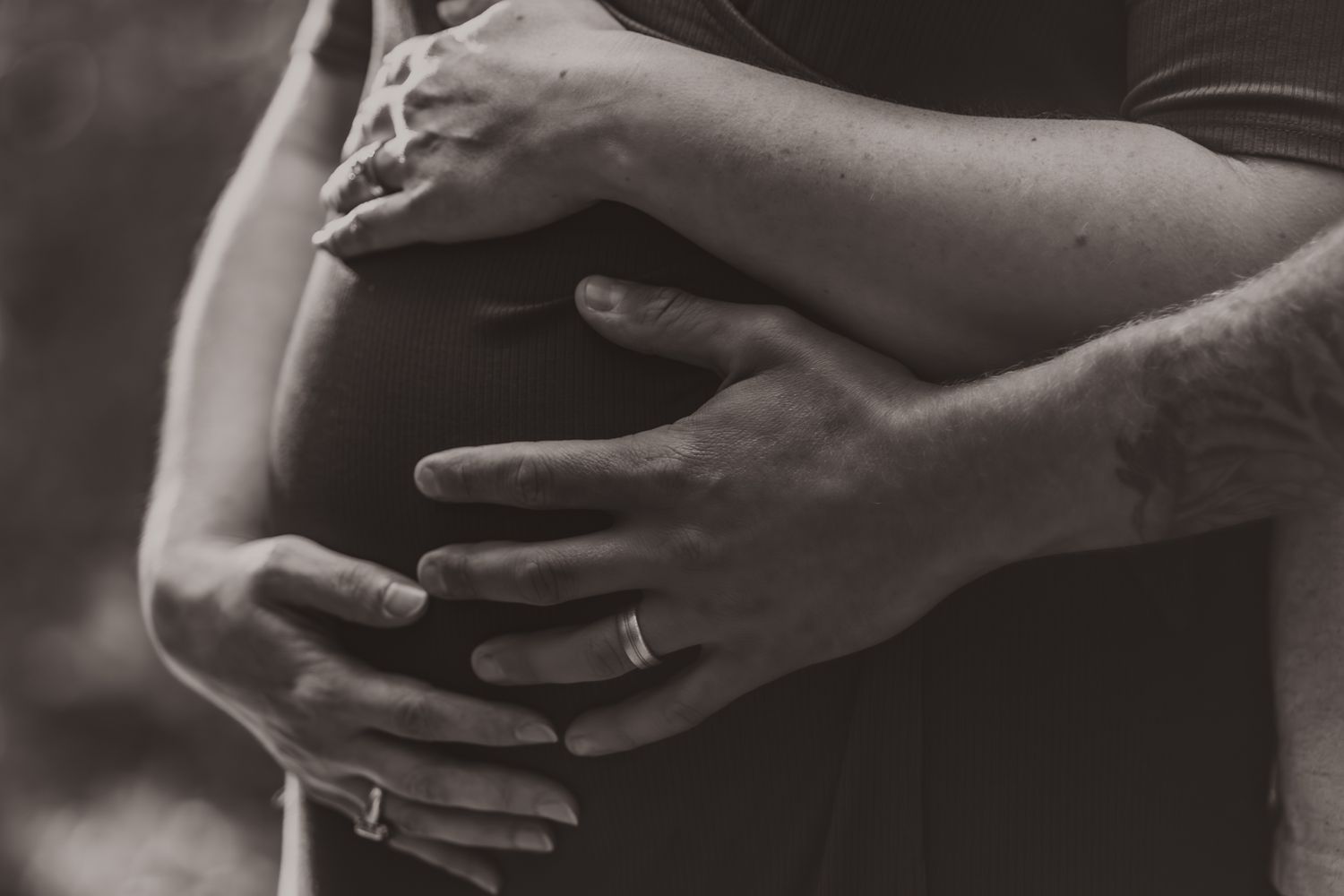 Black and white detail shot of hands tenderly touching during intimate moment.