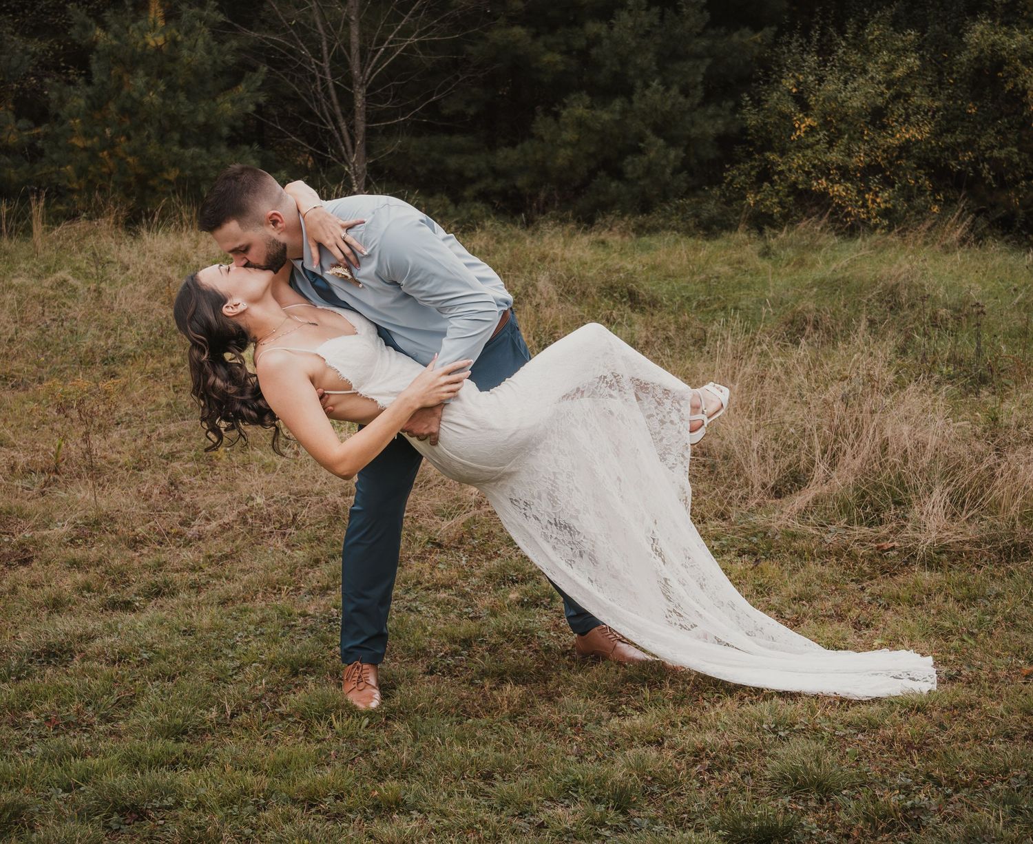 Romantic outdoor couple photo session with flowing white dress in grassy field.