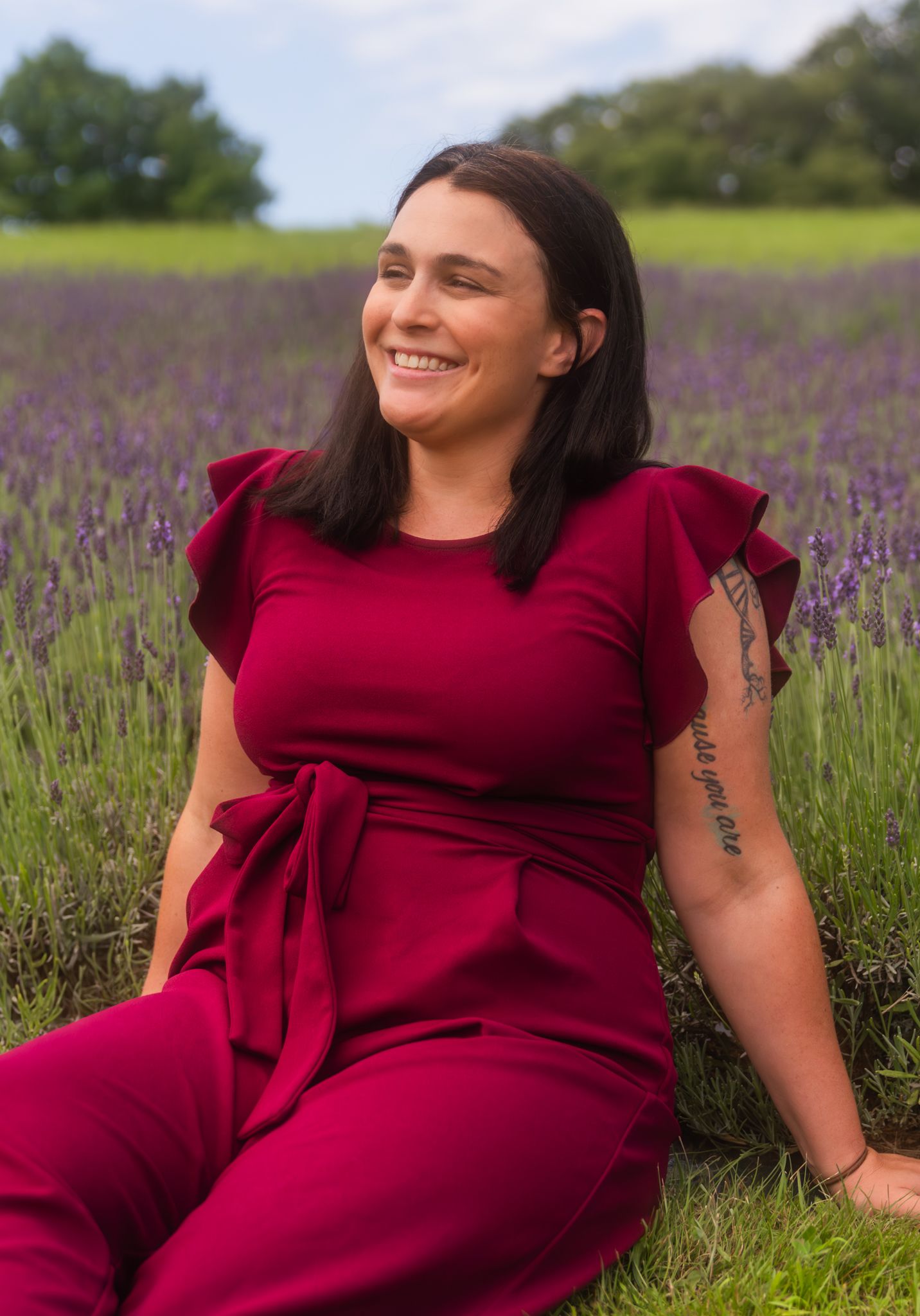 Portrait session in a blooming lavender field wearing a burgundy dress.