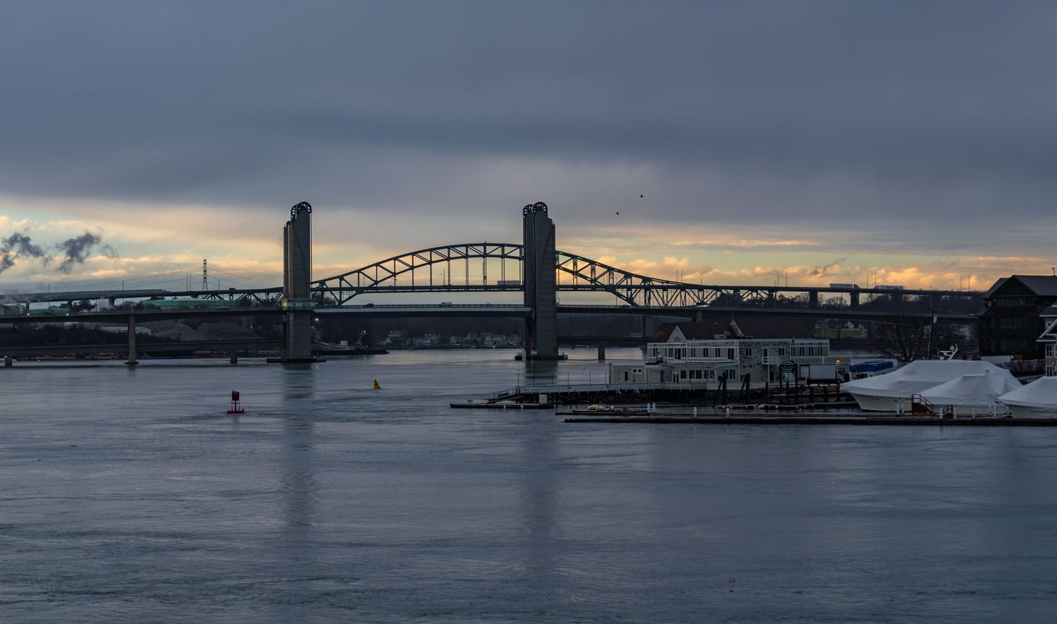 Industrial waterfront with drawbridge spanning river at dusk.