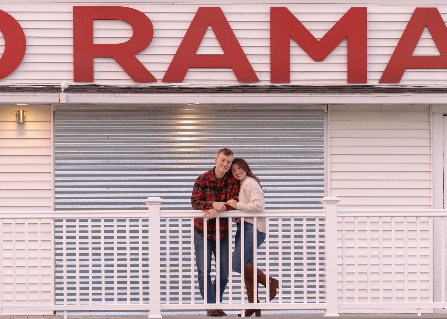 A couple sits together on a red and white storefront ledge.