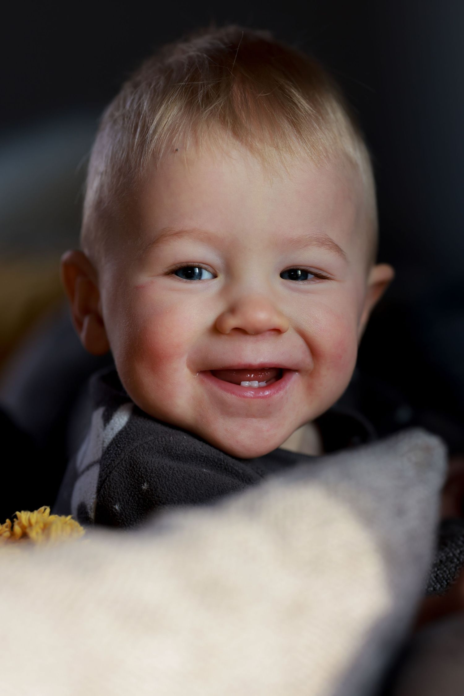 Close-up view of a smiling expression against dark background with soft lighting.