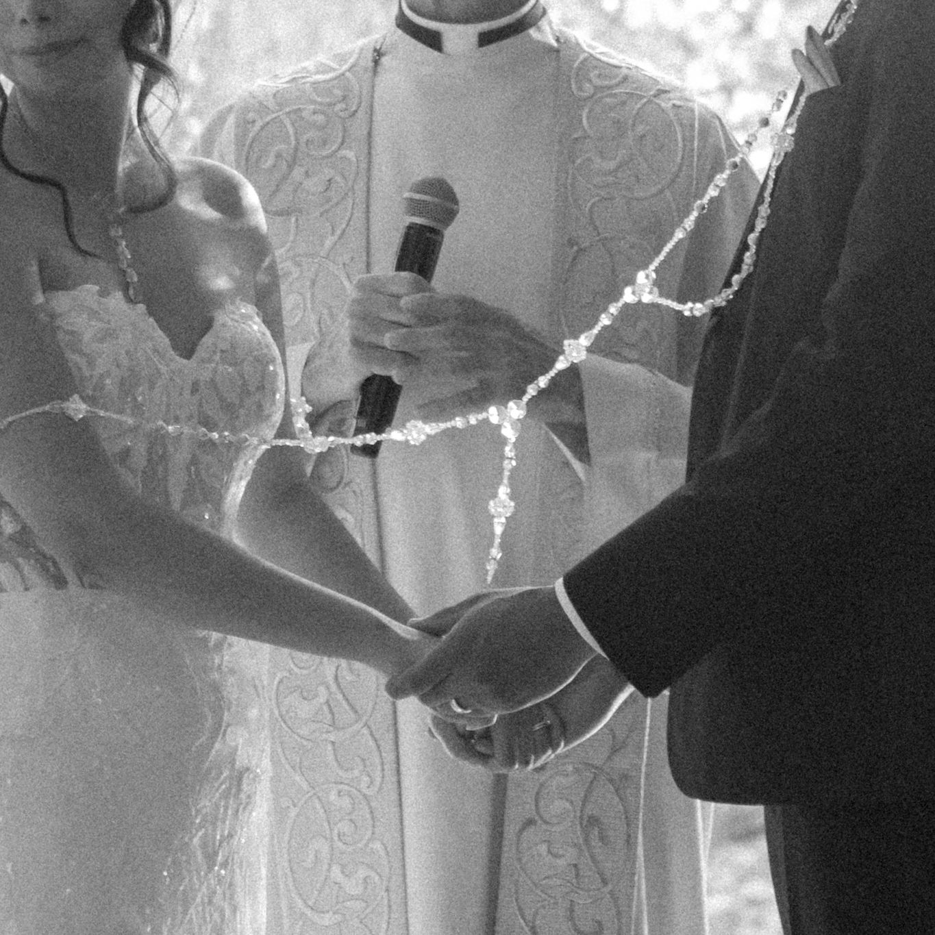 Priest officiates wedding ceremony as couple exchanges vows and holds hands.