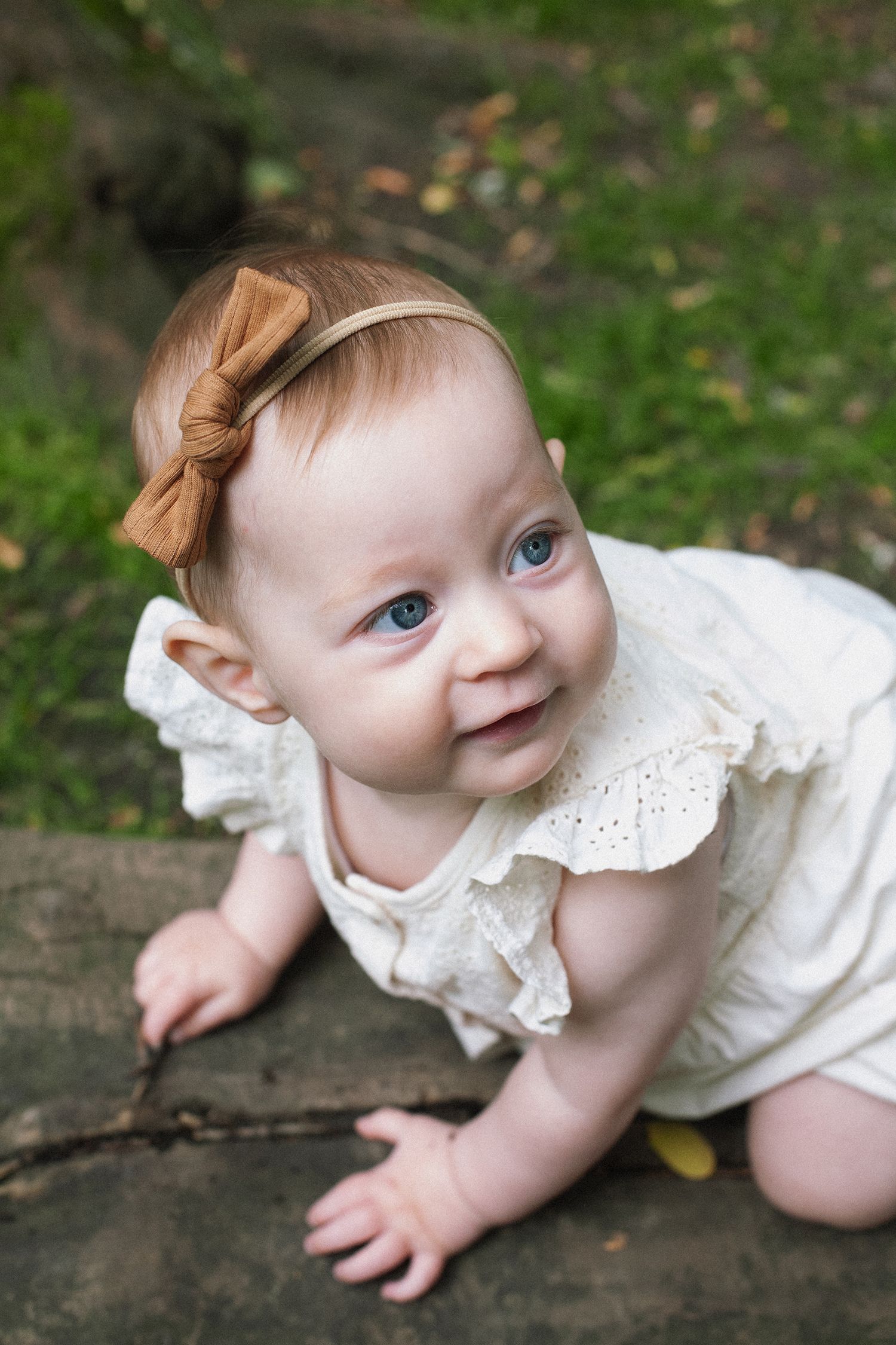 Series showing a baby in white lace dress crawling on wooden surface.