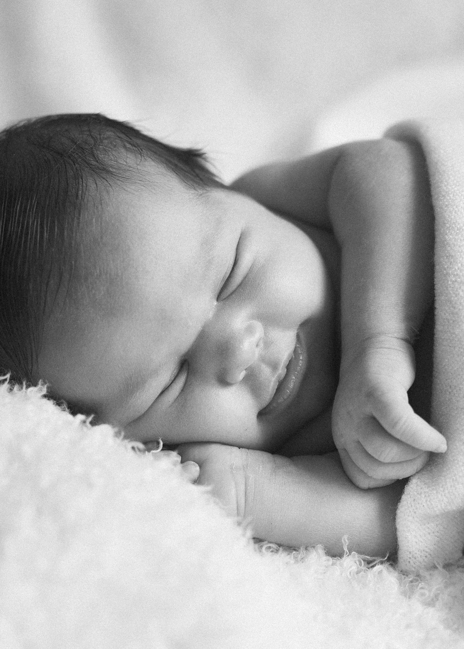 Sleeping newborn in black and white photography against white backdrop.