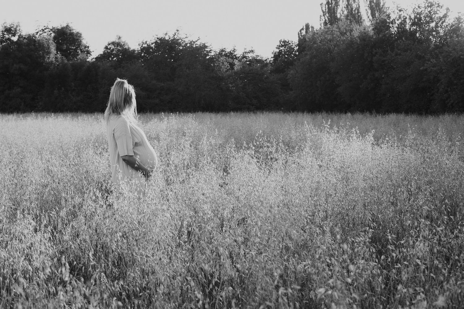 Ethereal black and white image of a figure standing in a misty field at twilight.