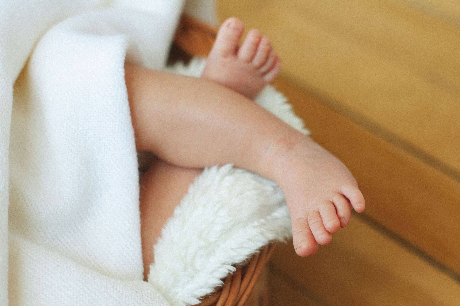 Close-up of tiny baby feet and toes on white textured surface.
