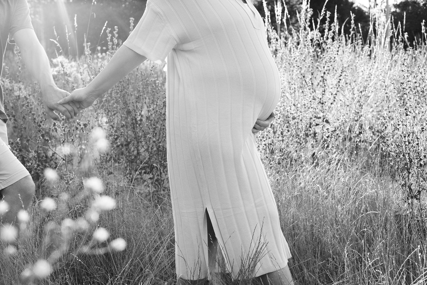 Dreamy maternity photography in a sun-drenched field of tall grass.