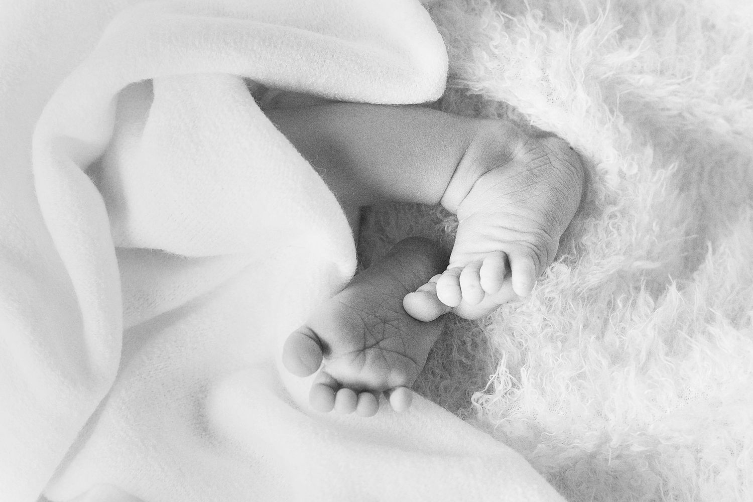 Minimalist black and white capture of baby's small feet on textured white fabric.
