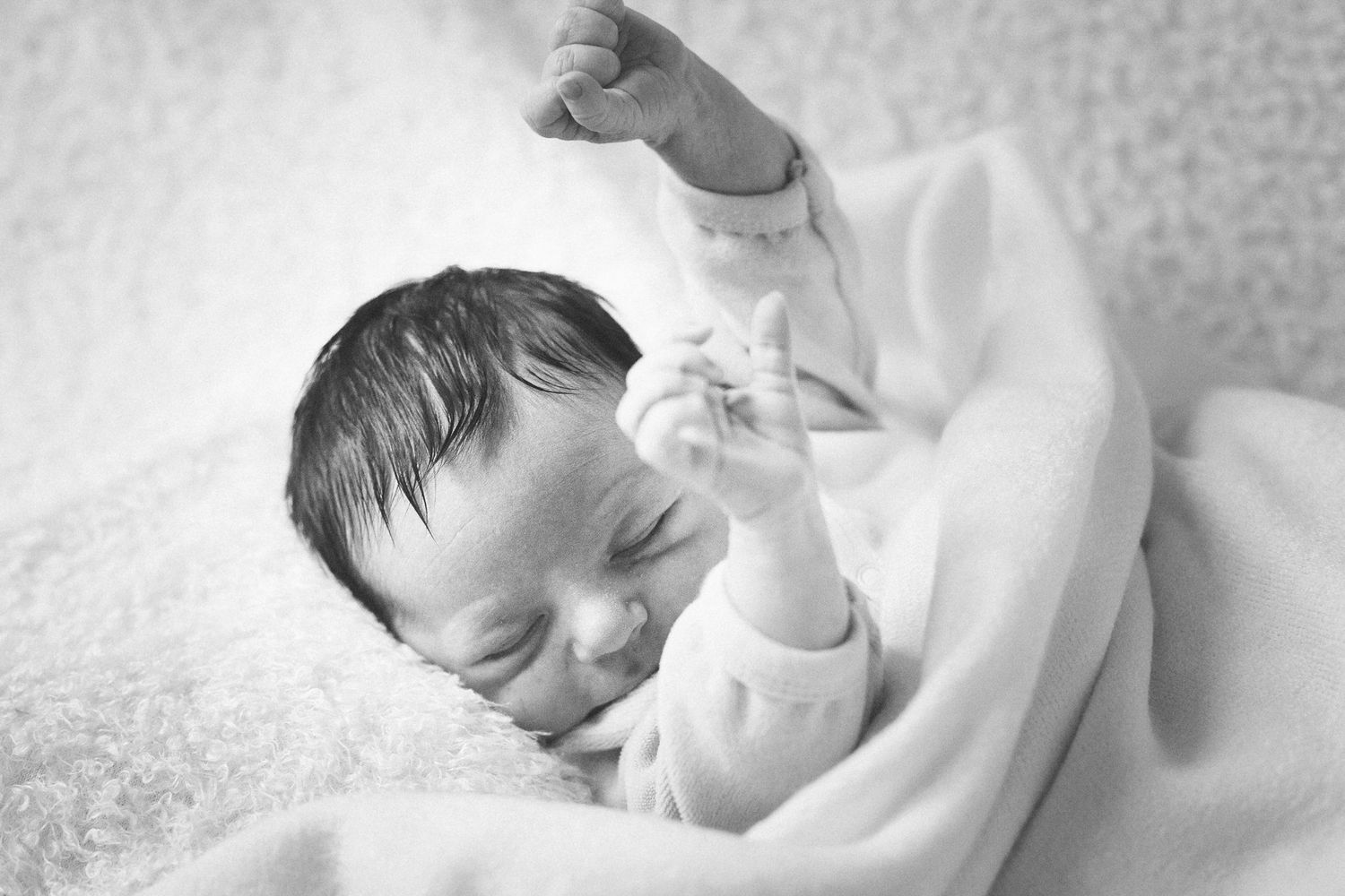 Series of peaceful newborn portraits in white swaddle blanket.
