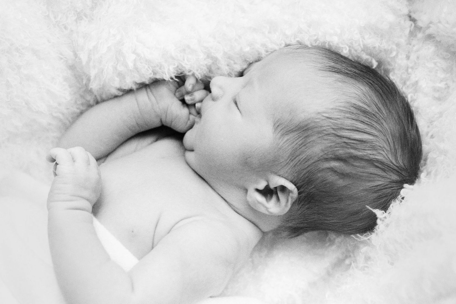 High key newborn photography showing peaceful sleeping baby on white background.