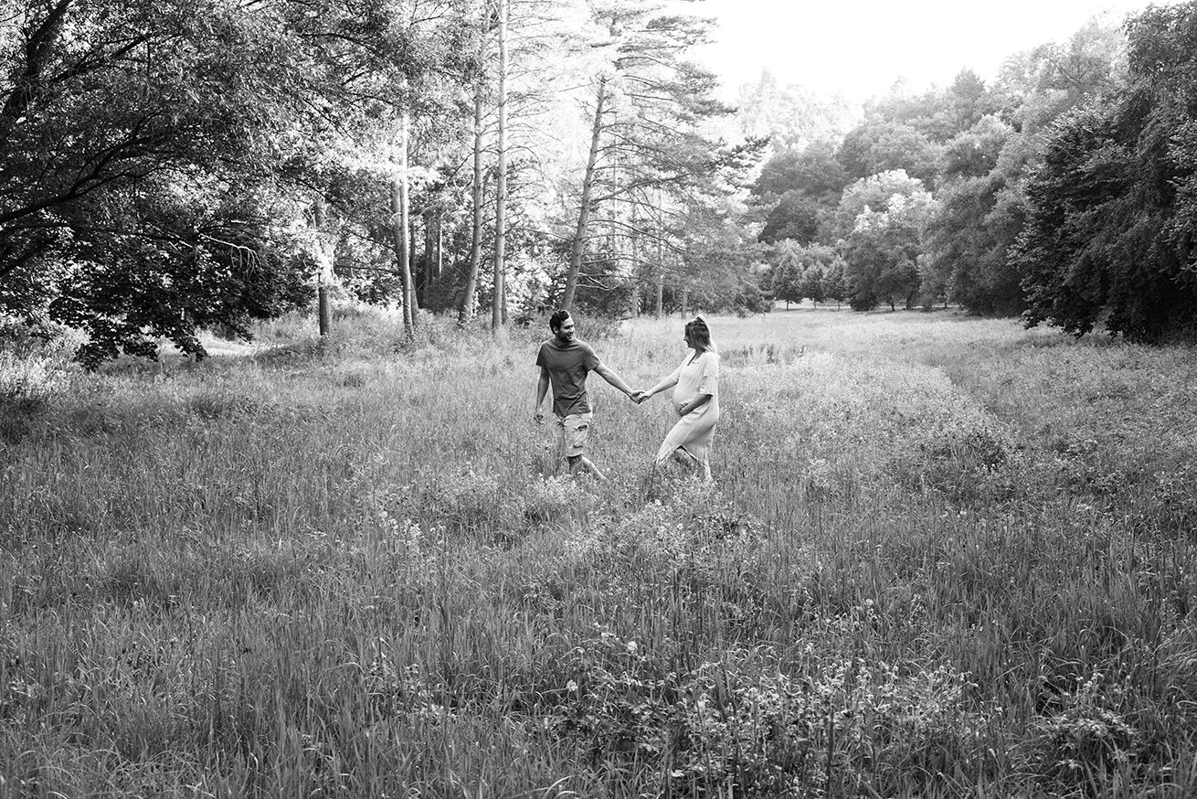 A sequence of black and white landscape photographs showing people walking through tall grass fields.