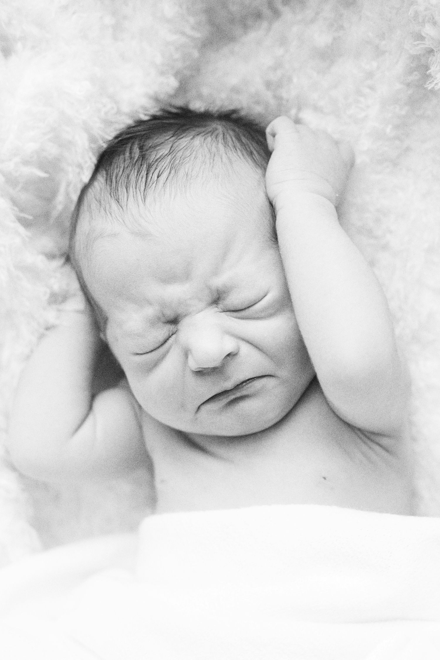 Close-up of sleeping newborn with delicate features against white backdrop.