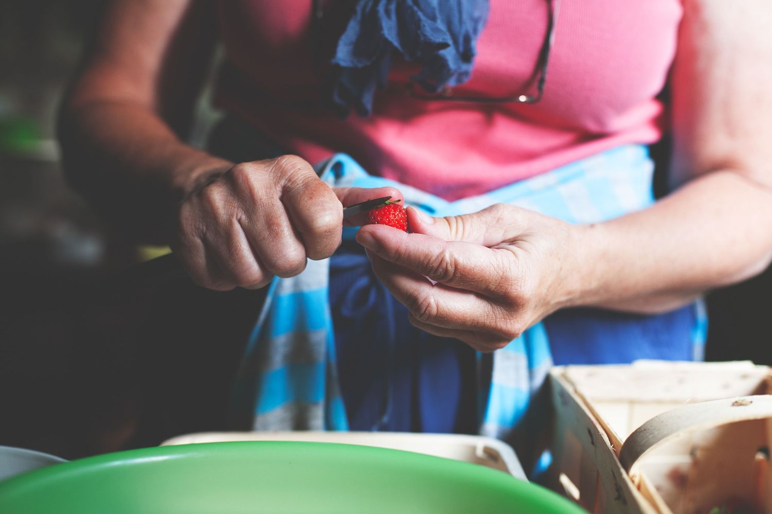 Close-up shot of hands holding items against a pink and blue clothing background.
