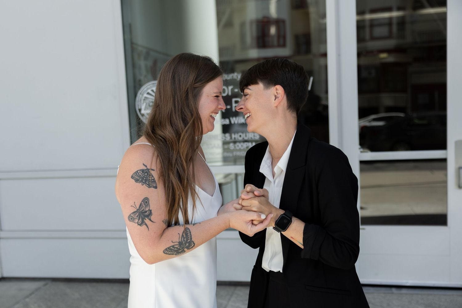 Two brides smile and laugh at each other after their ceremony outside of the courthouse by Taylor Zimmerman Photo