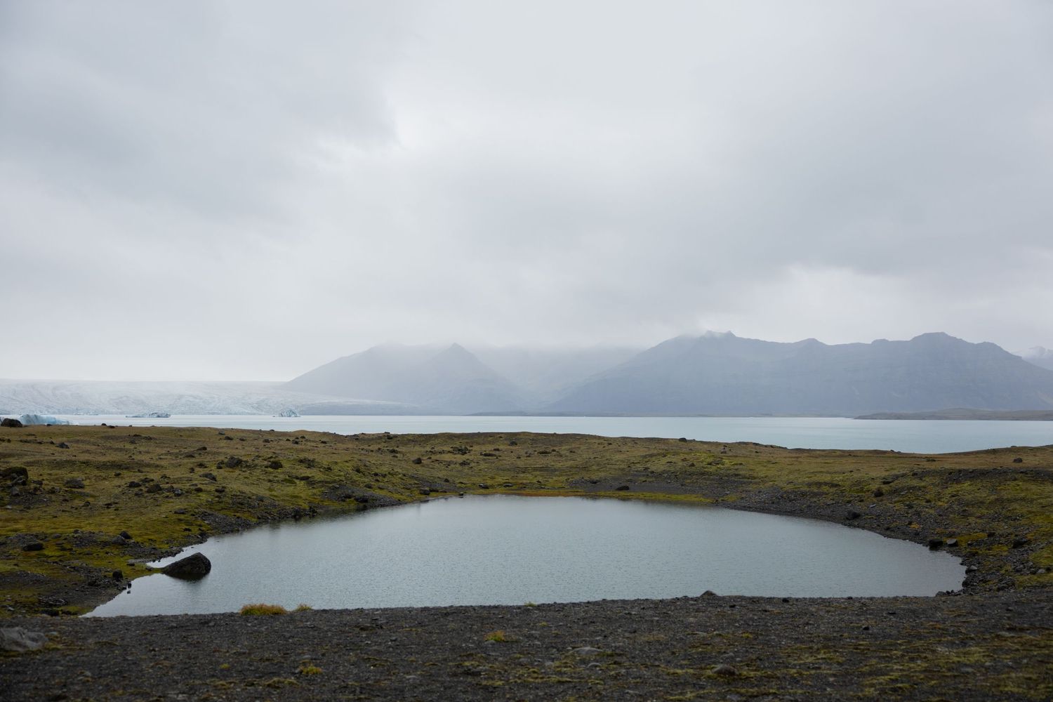 Wide landscape of Jokulsarlon glacier lagoon with misty mountains in Iceland by Taylor Zimmerman Photo