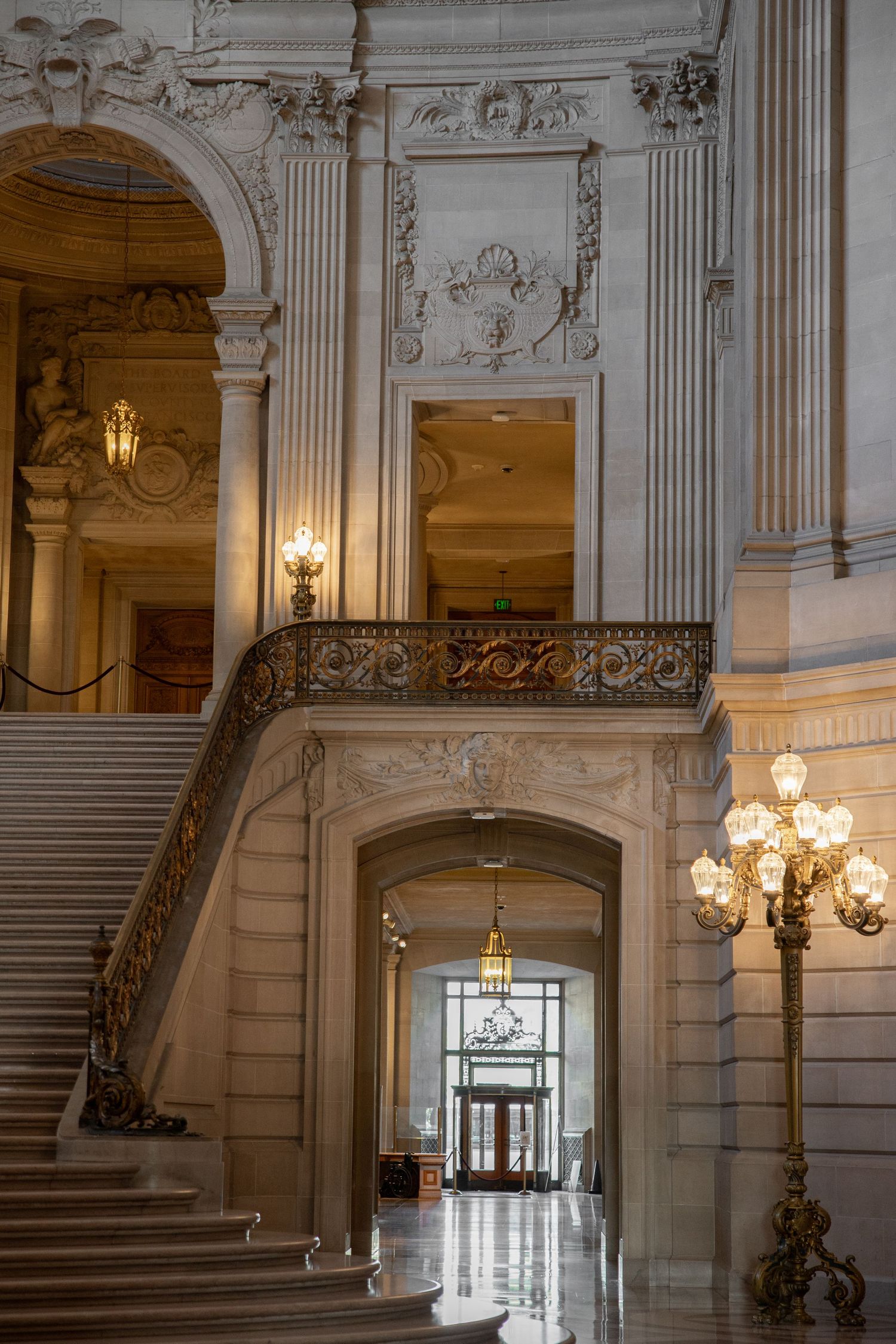 Part of the grand marble staircase and ornate gold lamp posts inside San Francisco City Hall's interior.