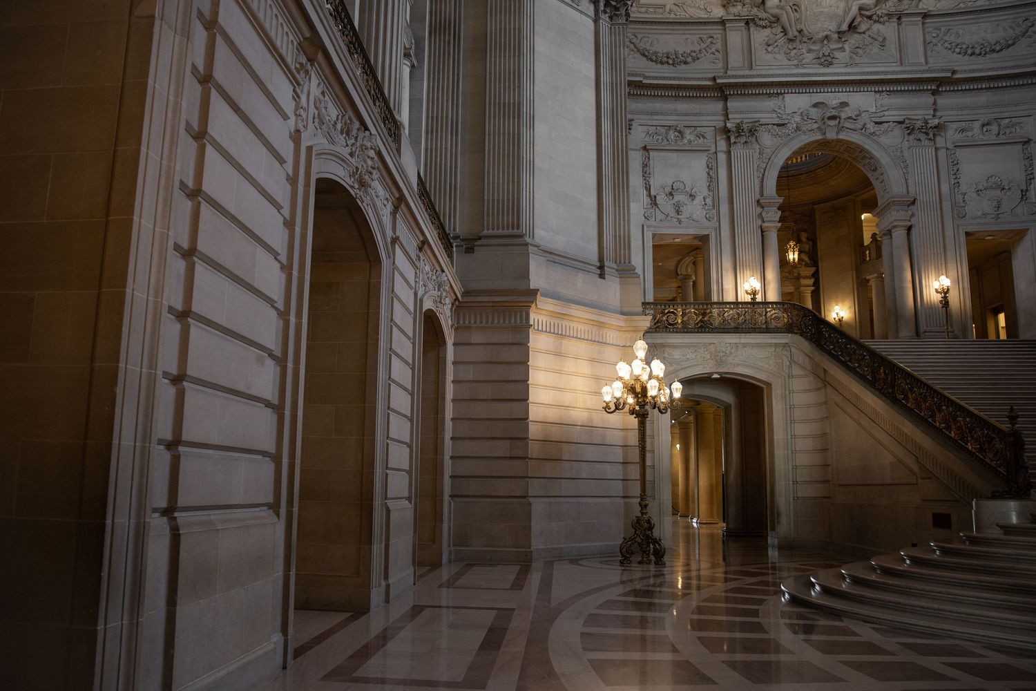 Grand marble interior of San Francisco City Hall featuring ornate staircase, chandelier, and elegant Beaux-Arts architecture.