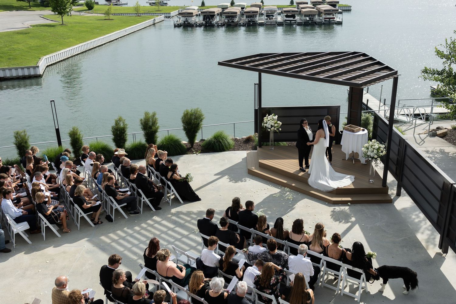 Outdoor wedding ceremony with guests seated at elegant pergola altar overlooking marina at a View at West Shores in Elkhorn, Nebraska