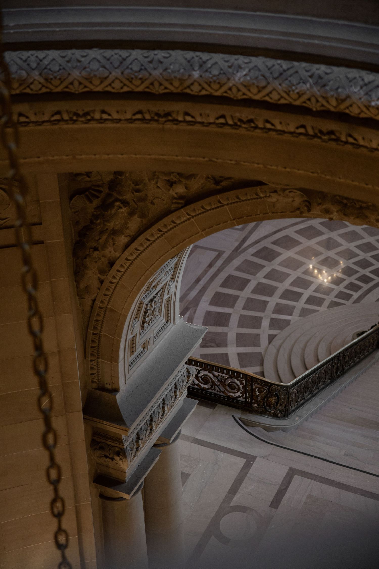 Ornate architectural arch with intricate gold detailing, coffered ceiling, and classical decorative moldings inside San Francisco City Hall.