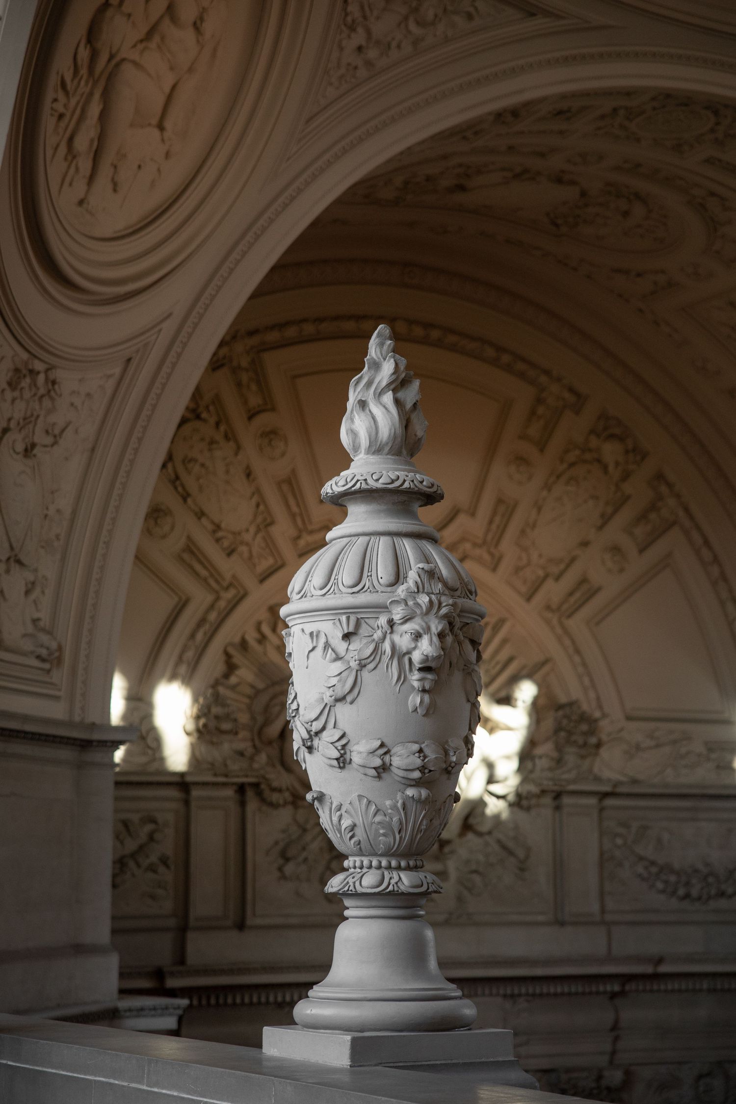 Ornate white marble urn with lion motif and flame finial displayed inside San Francisco City Hall.