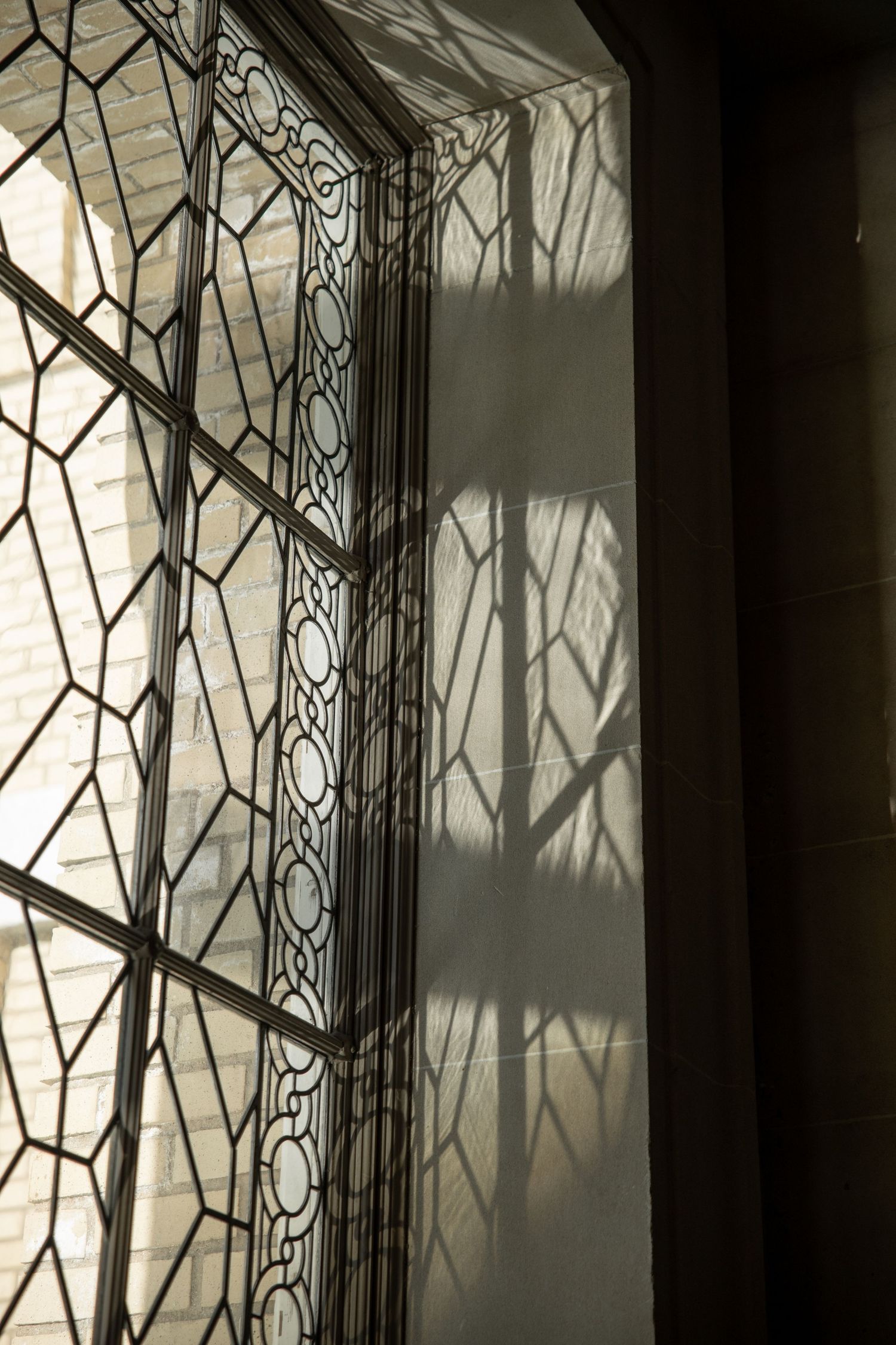 Sunlight filtering through a wrought iron window onto a wall of San Francisco City Hall.