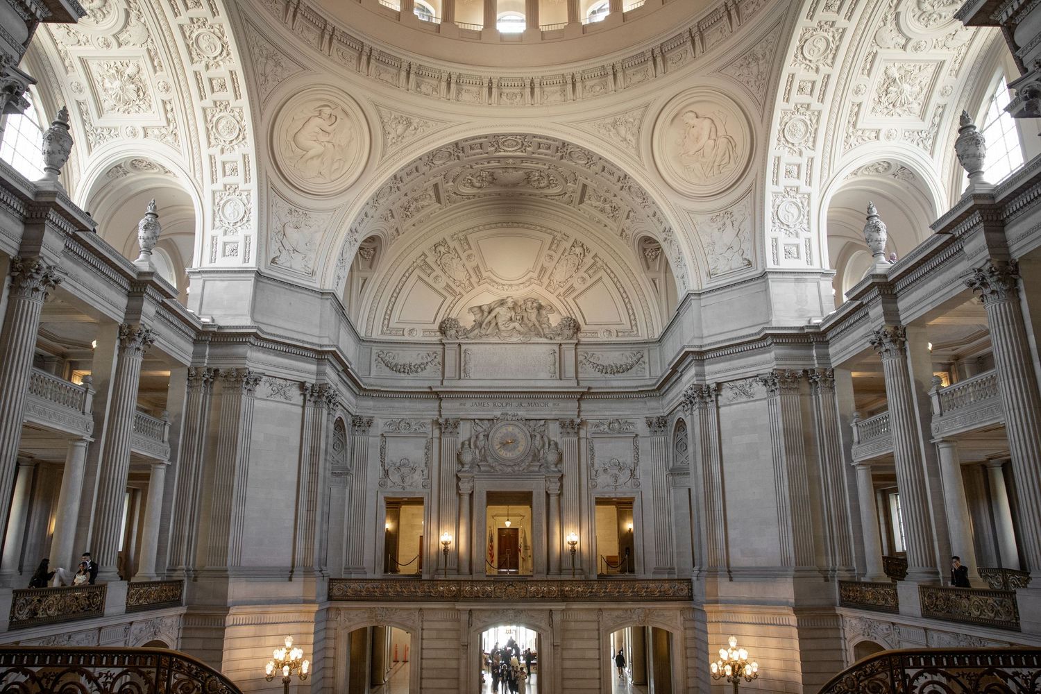 Grand interior rotunda of San Francisco City Hall featuring ornate architecture, arched ceilings, and elegant stone columns.