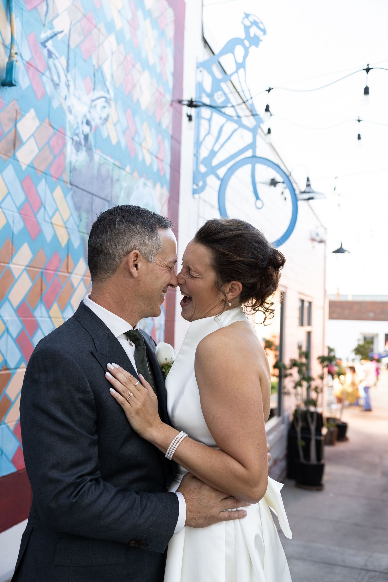 A joyful couple laugh with their faces close together in wedding attire against a colorful mural backdrop by Taylor Zimmerman Photo