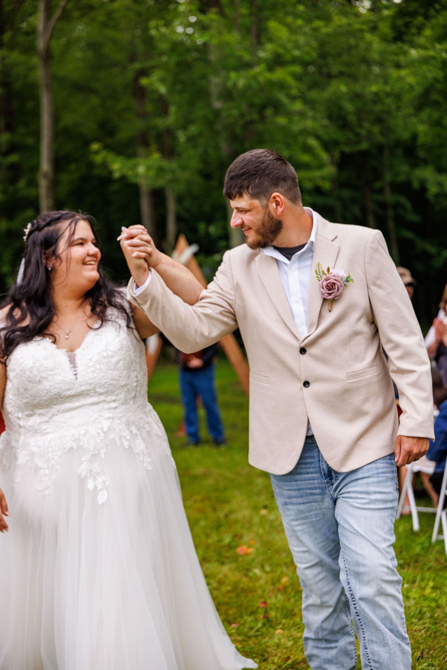 Smiling bride and groom walk hand in hand at their outdoor garden wedding ceremony.