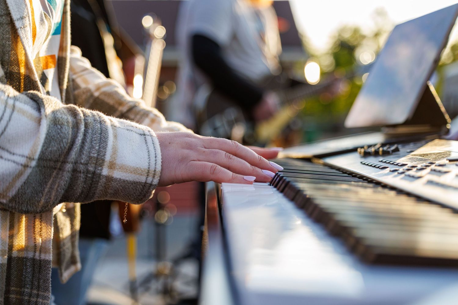 Close-up of hands playing a keyboard synthesizer at an outdoor worship music event.
