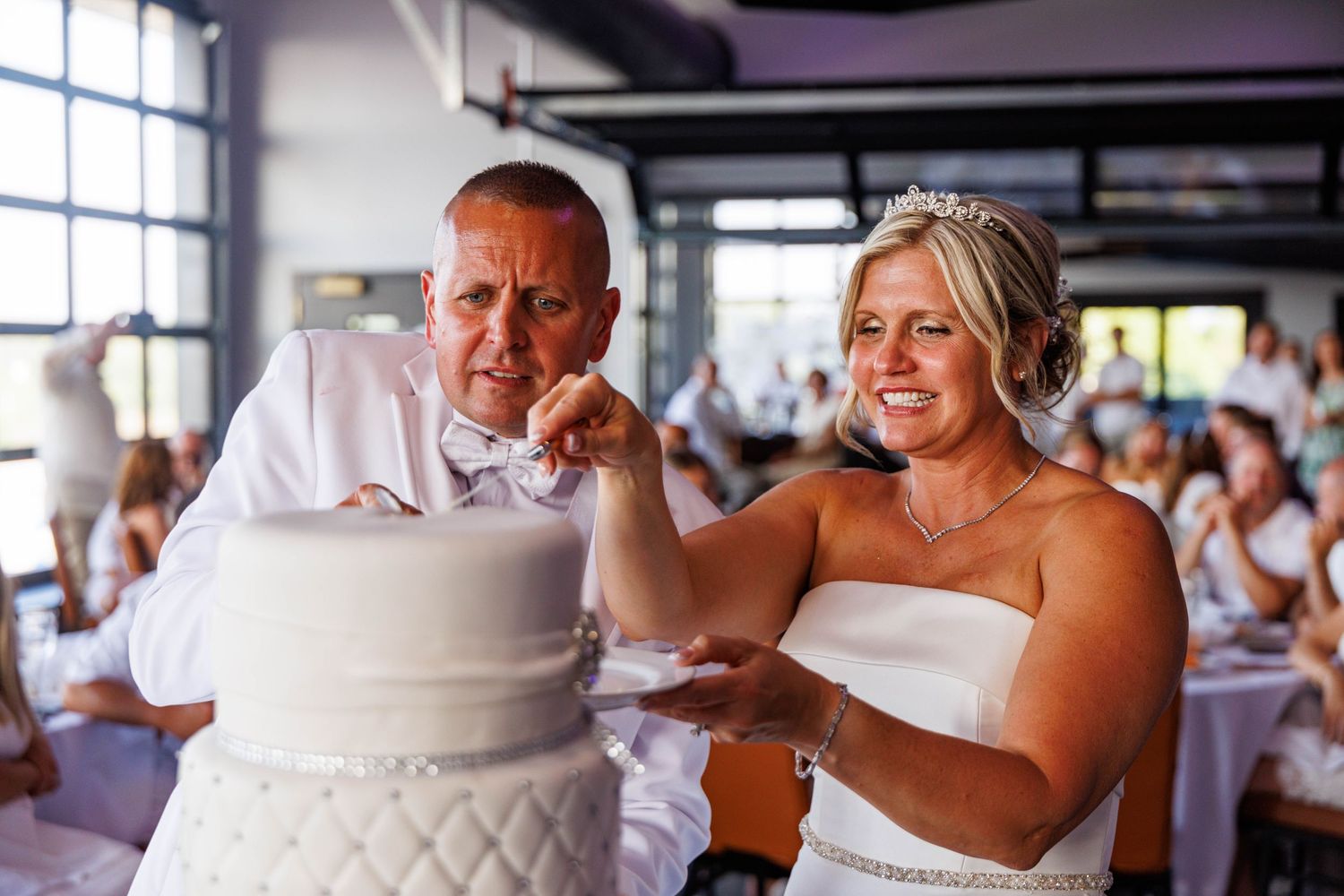 Bride and groom cut their white quilted wedding cake together at their reception.