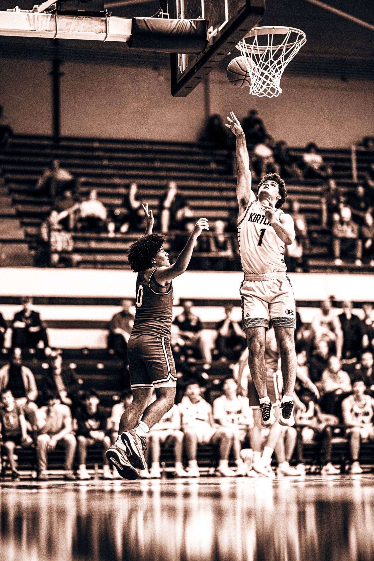 Basketball player in white jersey laying up the ball over a defender.