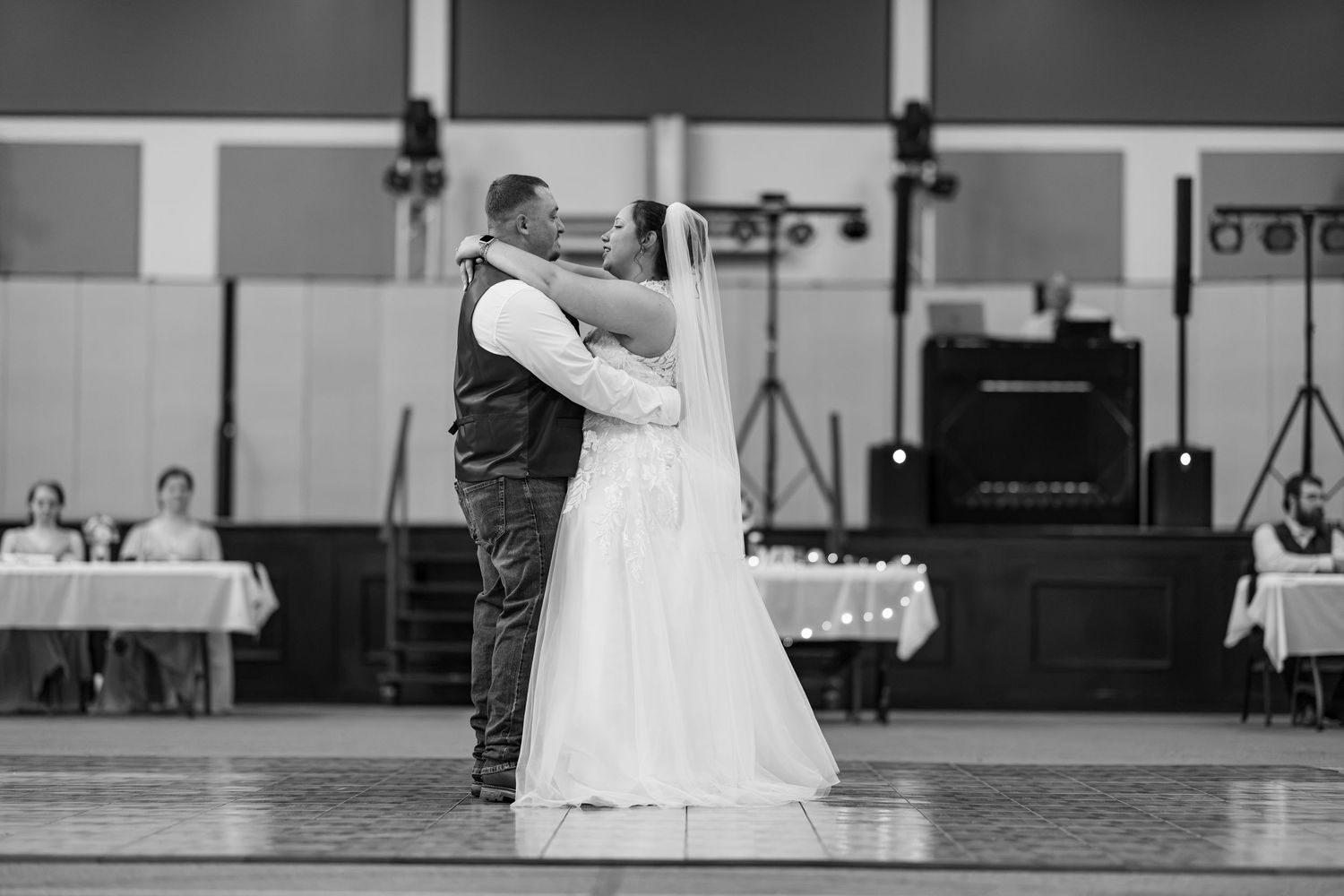 Couple sharing romantic first dance at wedding reception in black and white.