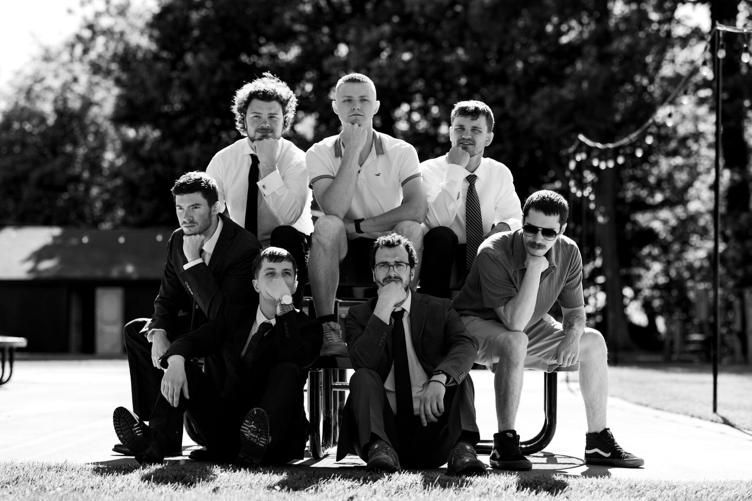 A fun black and white group photo of groomsmen posing together outdoors on the wedding day.
