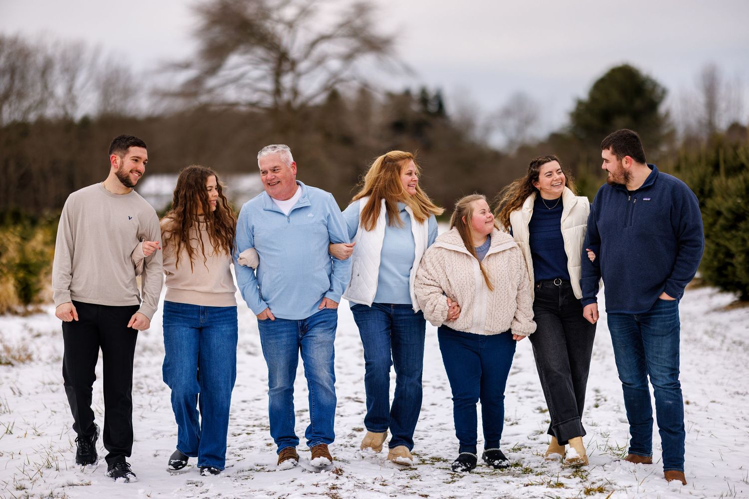 Family of seven walking together hand in hand across a snowy field in winter.
