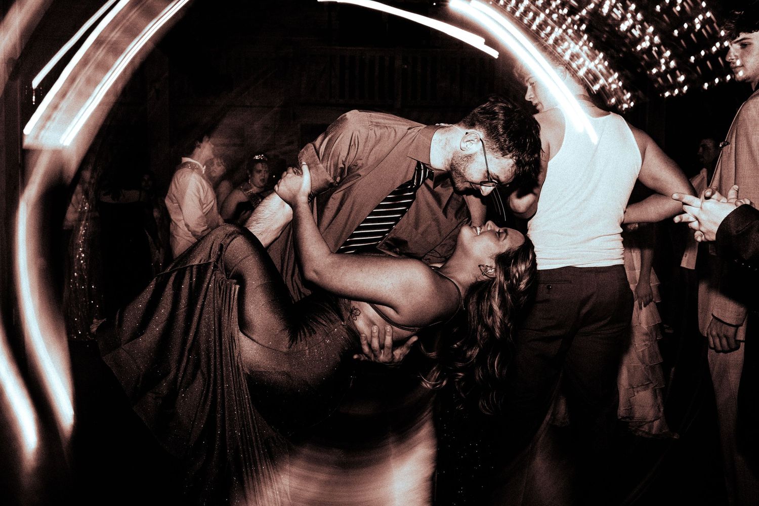Black and white dramatic photo of a couple sharing a romantic kiss on the dance floor at prom.