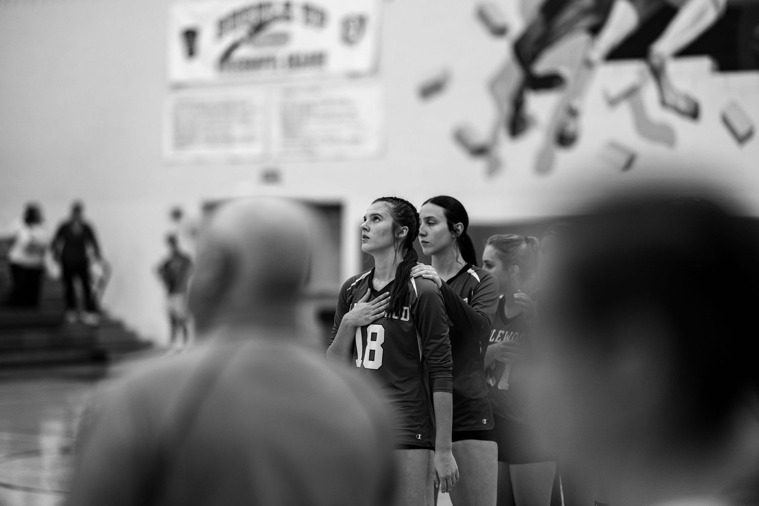 Black and white photo of two female volleyball players in jerseys standing attentively during a match.