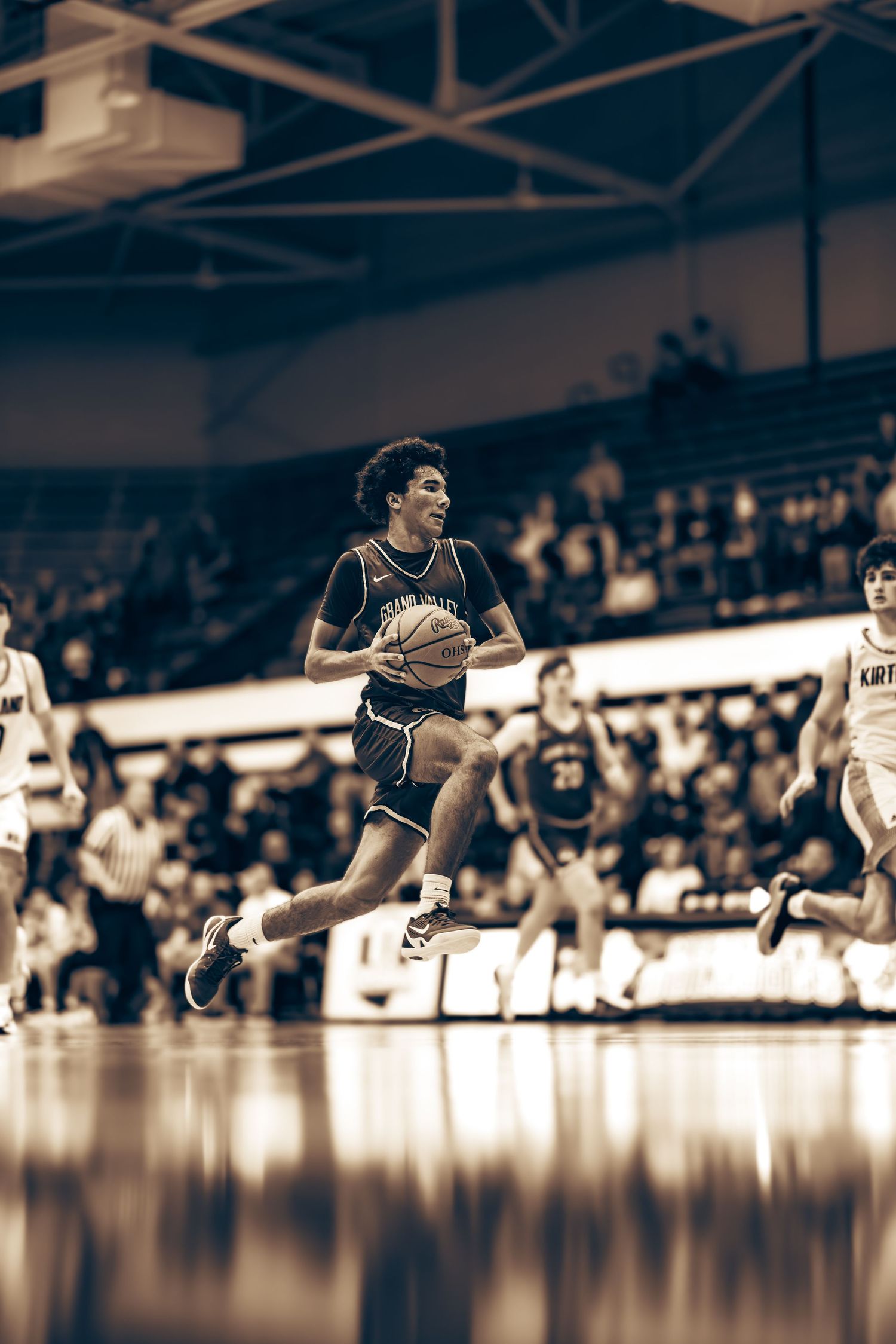 Basketball player driving to the basket during a competitive college game.