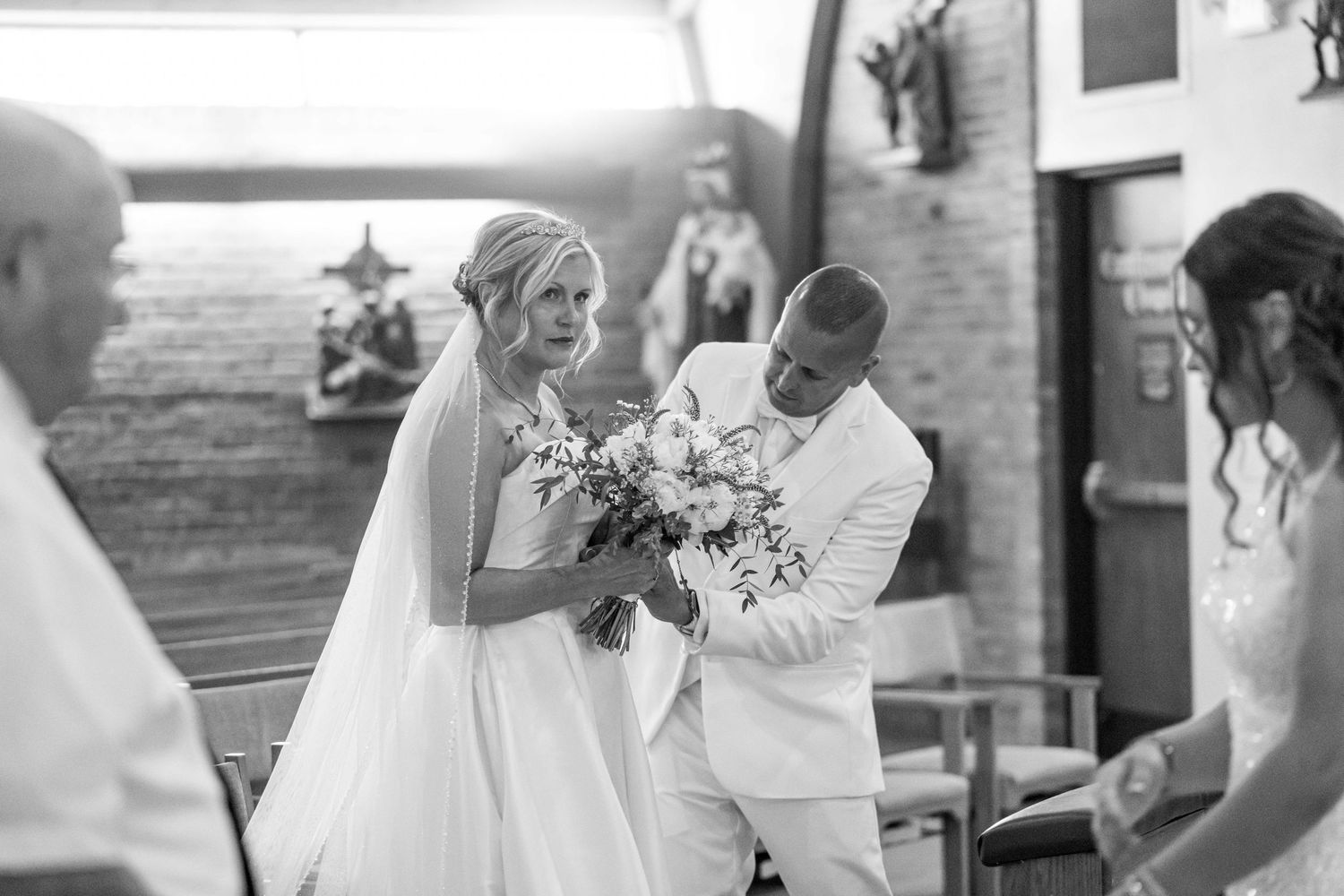 Bride and groom share a joyful moment during their wedding ceremony, with the bride holding a beautiful bouquet.