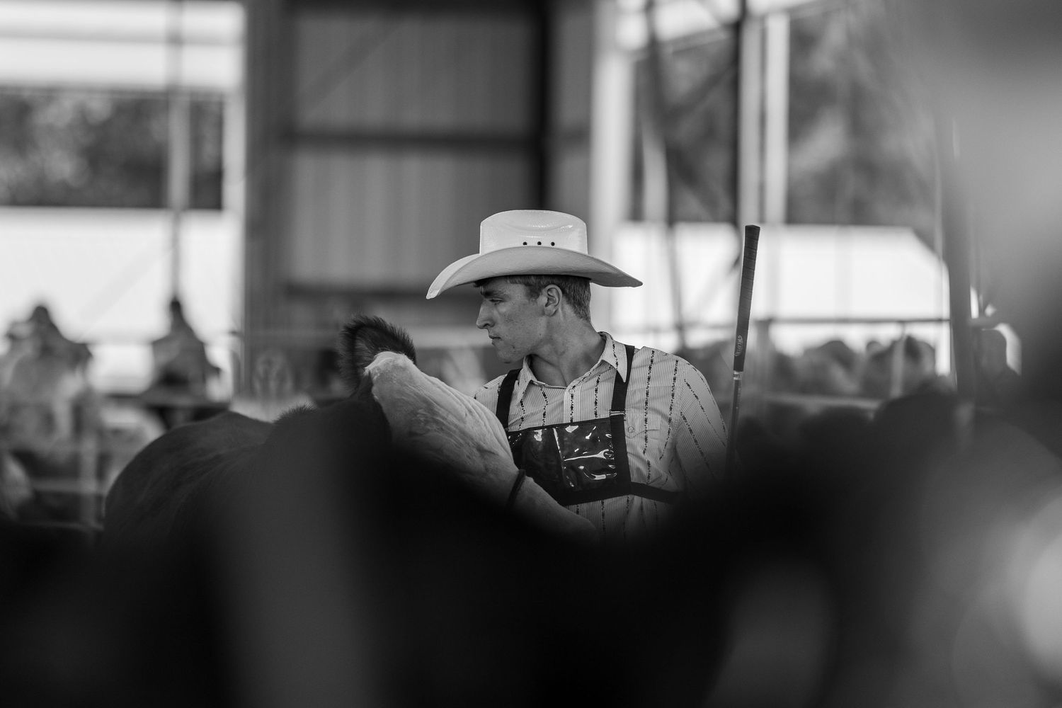 Black and white portrait of a young man wearing a cowboy hat at a livestock show event.