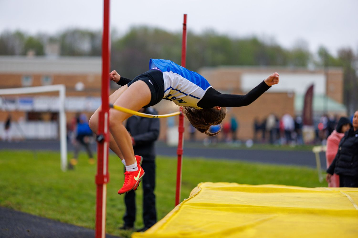 Athlete performing a high jump over the bar at a track meet.