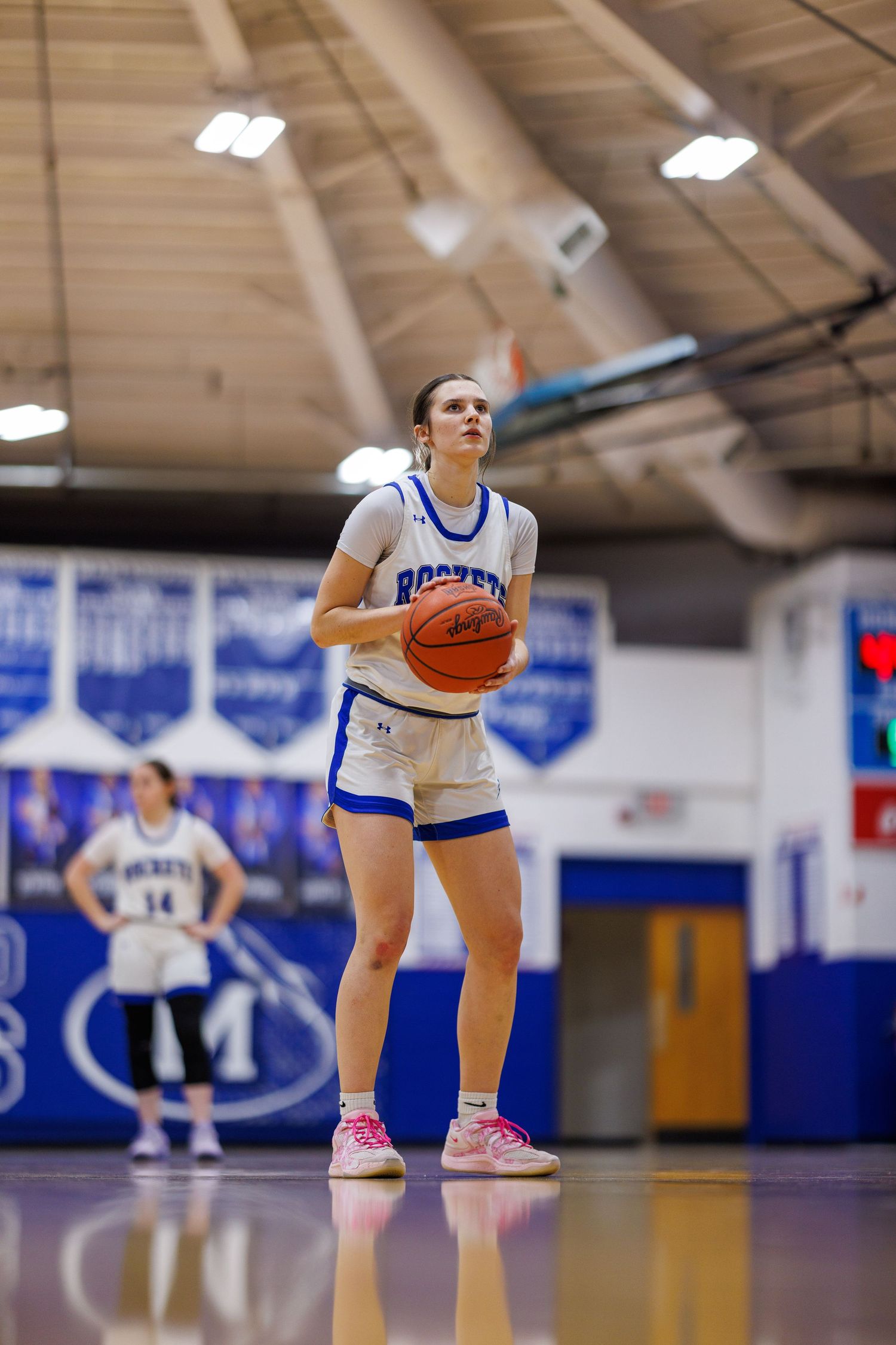 Female basketball player in blue Rockets uniform prepares for a free throw shot in an indoor gymnasium.