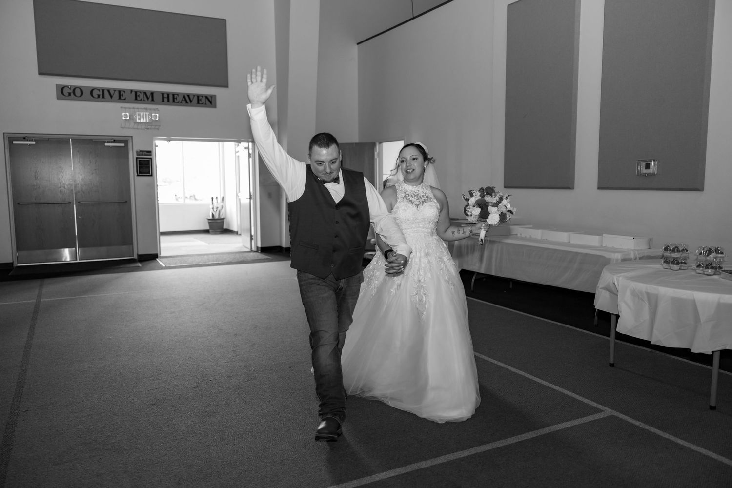 Bride and groom entering wedding reception hall in black and white photo.