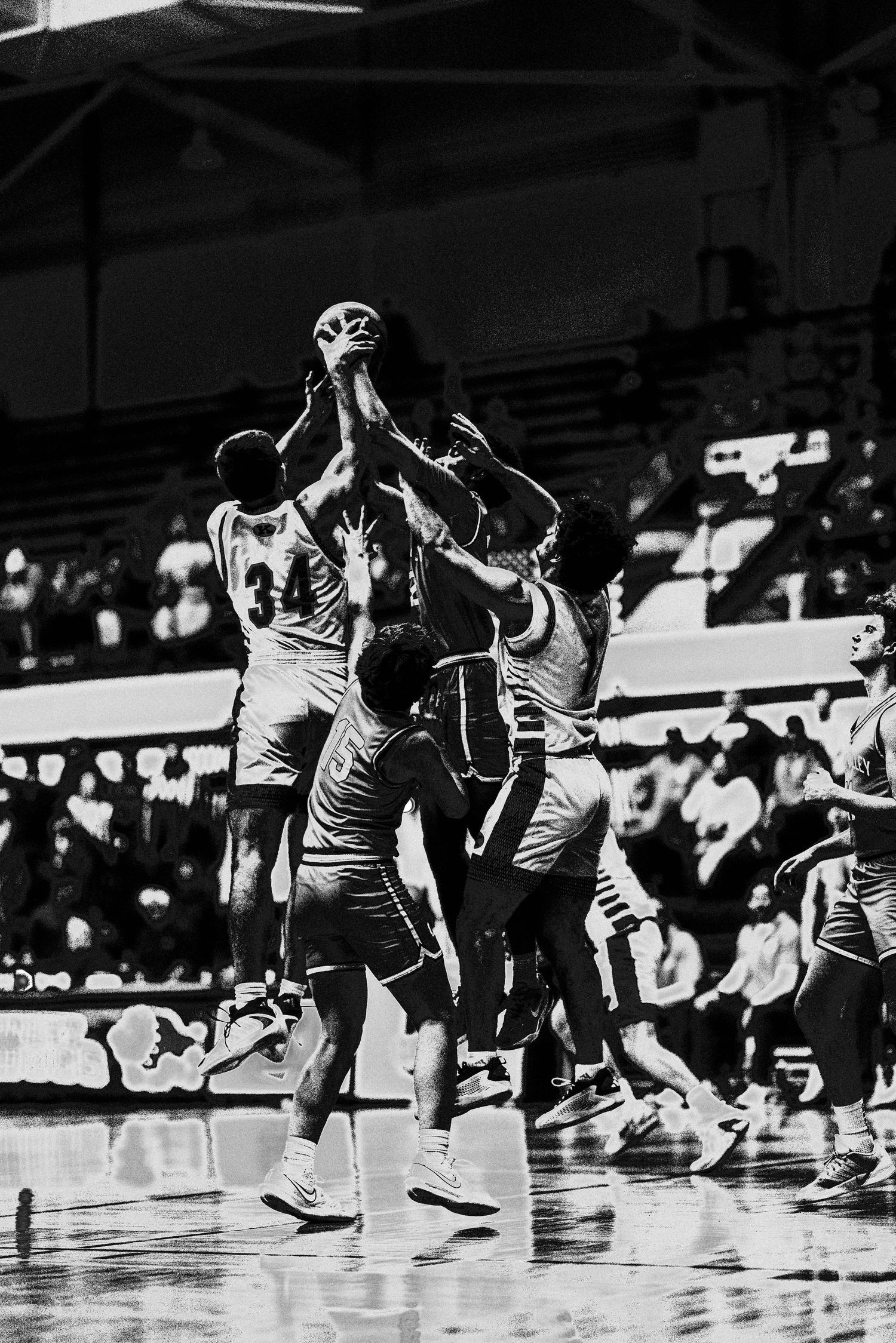 Multiple basketball players jumping for a contested rebound during a game.