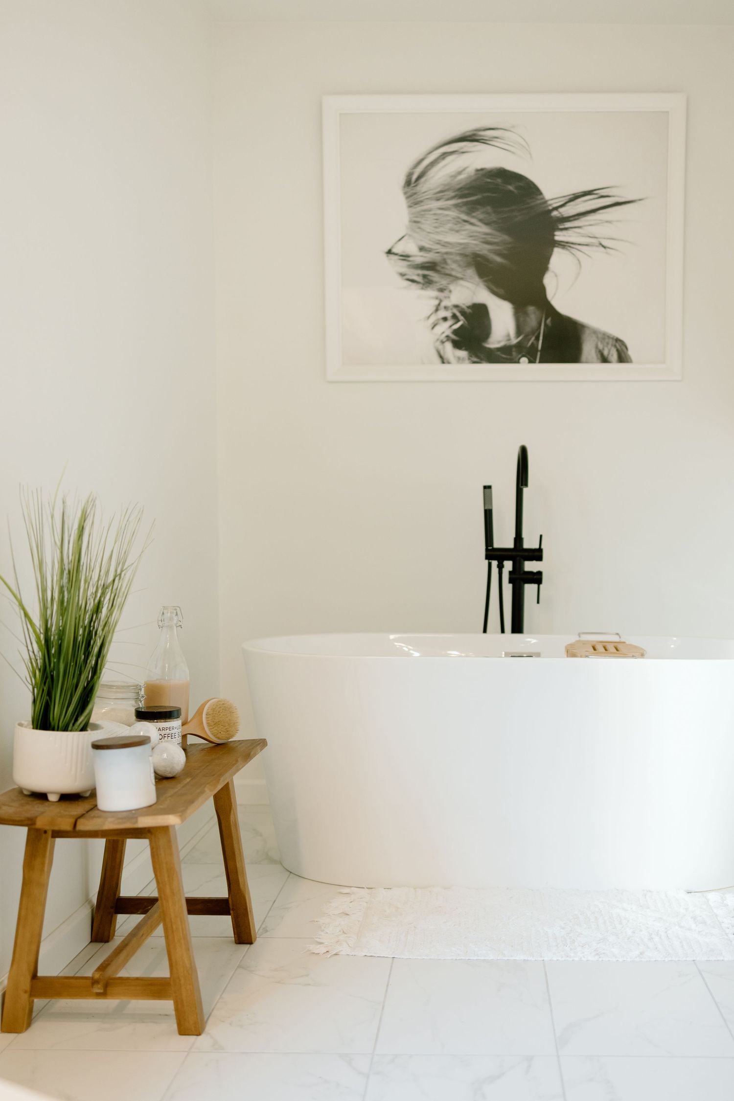 Bright white bathroom with freestanding tub, black faucet, and black-and-white wall art.