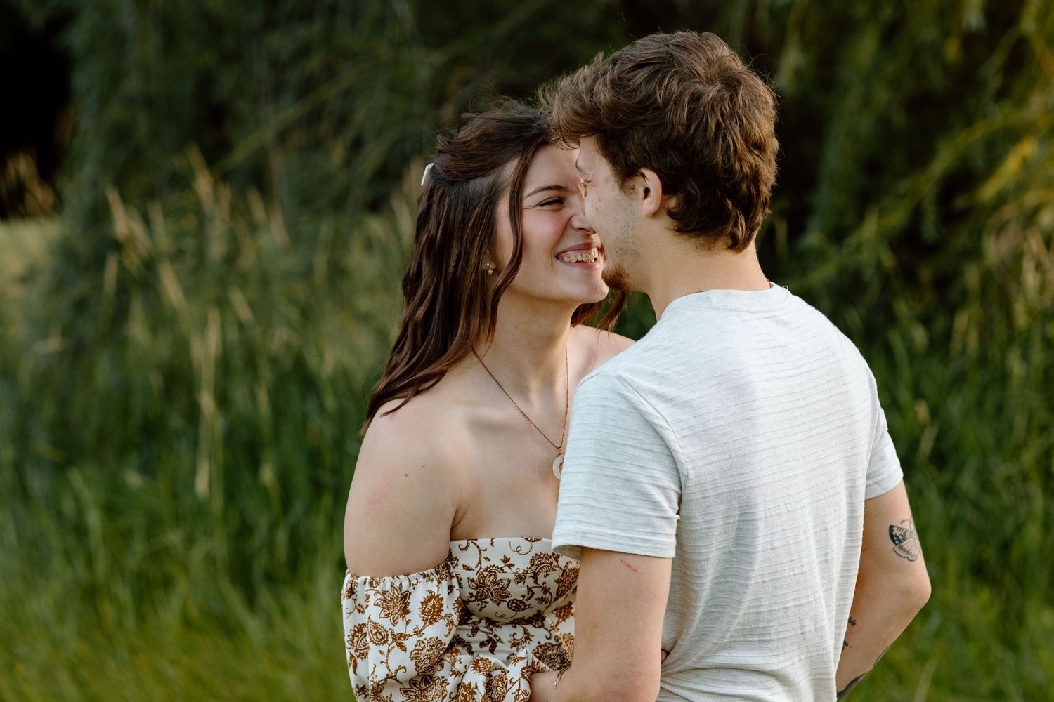Young couple sharing a romantic moment face-to-face in a green outdoor setting.