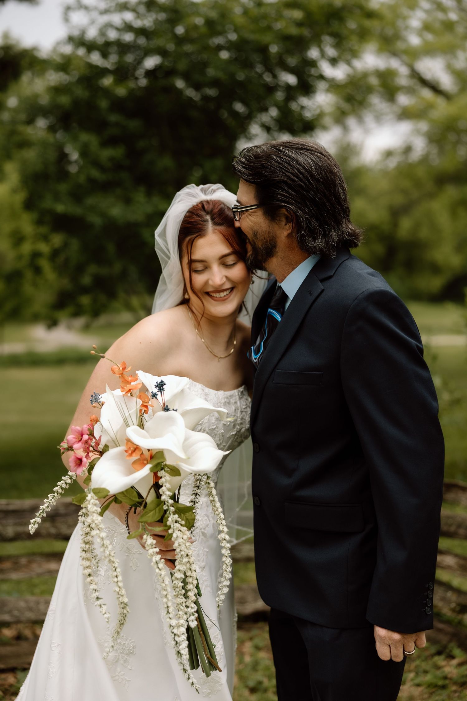 Bride and groom sharing intimate moment outdoors, bride laughing while holding floral bouquet.