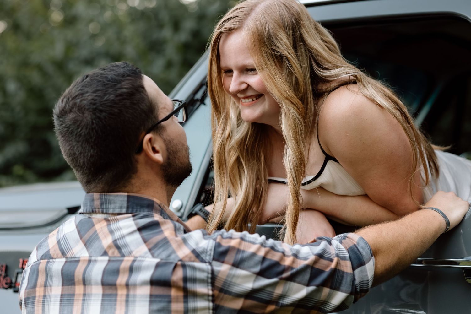 Couple sharing a joyful moment together near a truck outdoors, man holding woman as she leans down smiling.