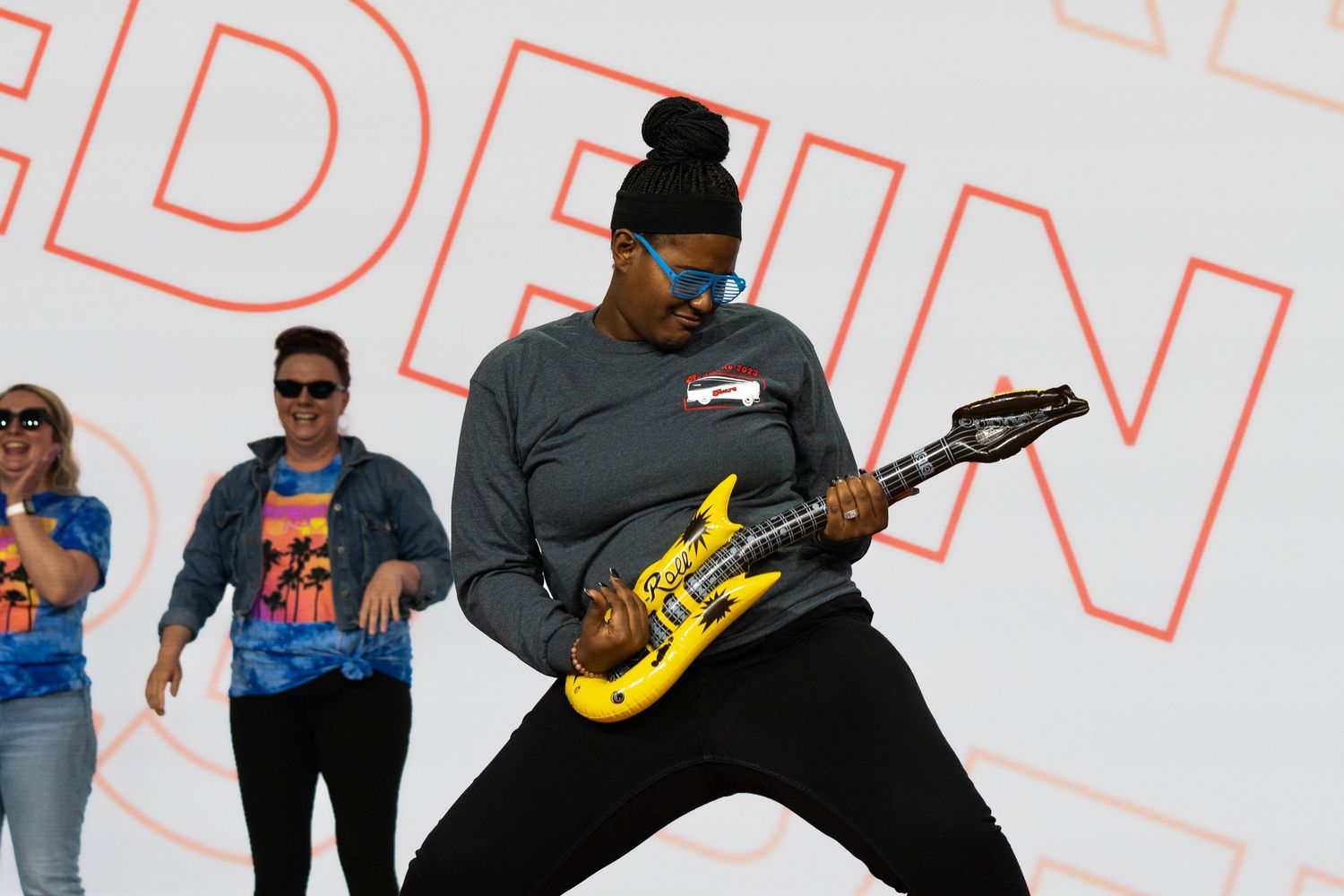 Photo of professionals on stage playing an inflatable guitar during an experiential activation.