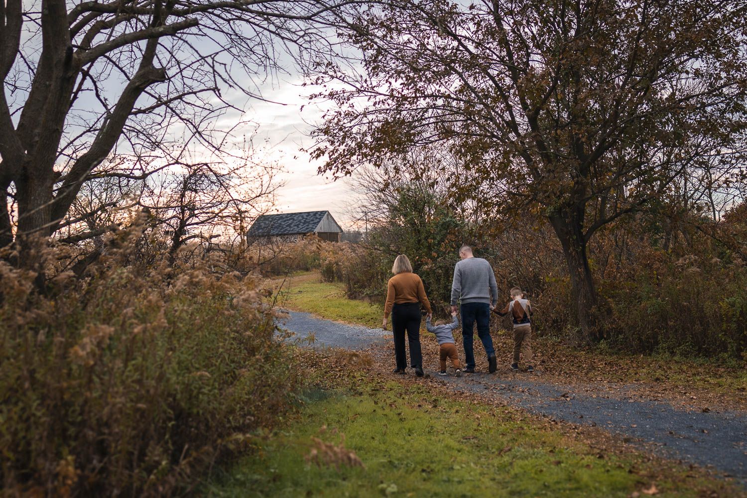 Family walking along pathway during fall family photo session at Swedes Run in Moorestown, NJ